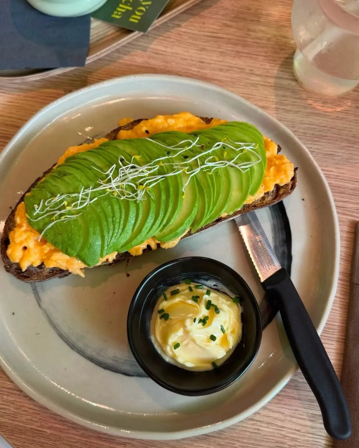 Avocado-Toast mit Rührei und Kresse, daneben Kräuterbutter
